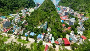 A coastal town with a prominent hill, dense greenery, and a view of the sea with boats. - Phu Thanh Sea View Hotel (Hai Phong)