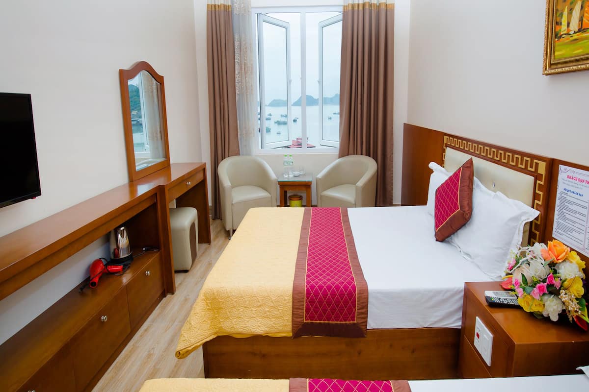 A hotel room with a bed, a desk, a chair, a TV, and a window with curtains.