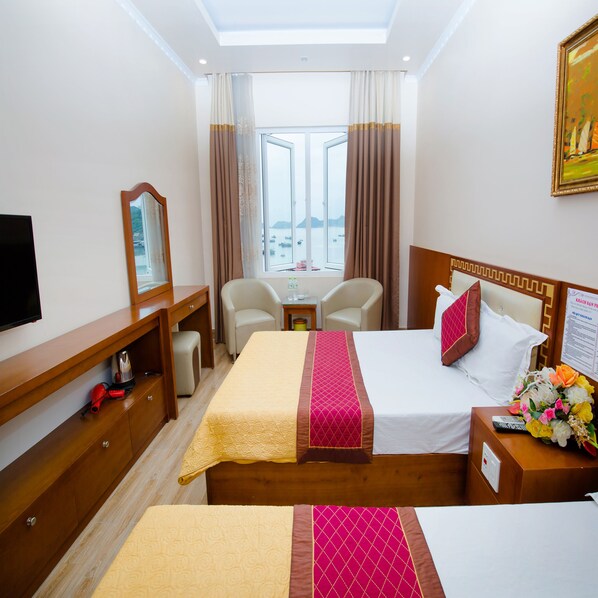 A hotel room with a bed, a desk, a chair, a TV, and a window with curtains.