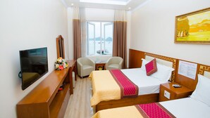 A hotel room with a bed, a desk, a chair, a TV, and a window with curtains. - Phu Thanh Sea View Hotel (Hai Phong)