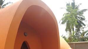 A uniquely shaped orange building with a welcoming sign at the entrance. - Pumpkin Villa  Lombok (Senggigi)