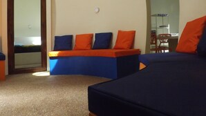 A room with a bed, a bench with cushions, a mirror, and a door. - Pumpkin Villa  Lombok (Senggigi)