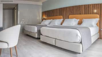 A modern hotel room with a large bed, a bedside table, a chair, and a wooden accent wall.