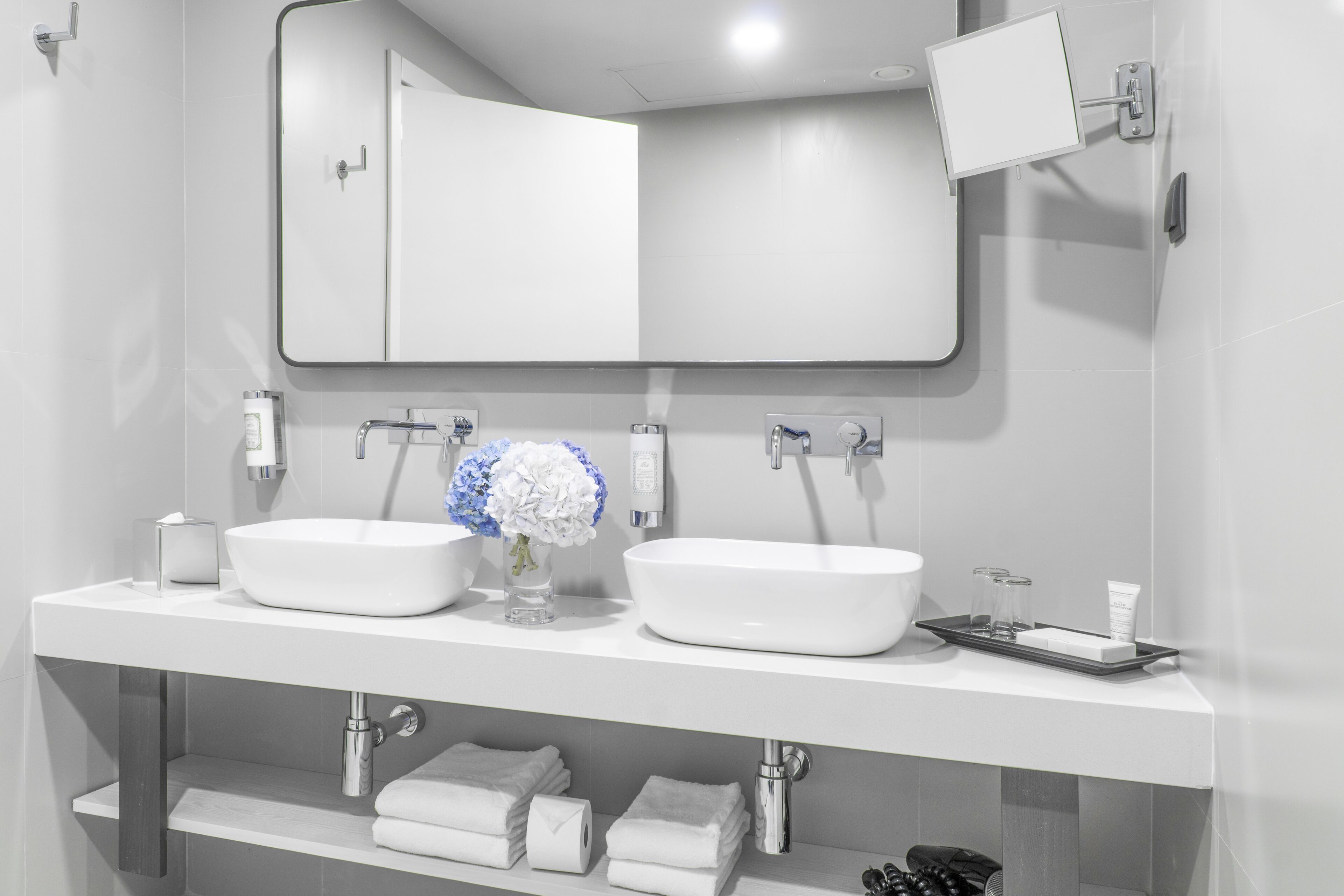 Une salle de bain moderne avec deux lavabos, un grand miroir et un porte-serviettes.