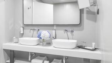 A modern bathroom with two sinks, a large mirror, and a towel rack.