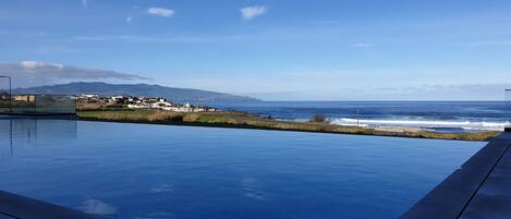 Una piscina con vista al océano y una cadena montañosa distante.