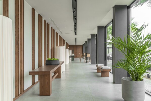 A modern hallway with wooden panels, a bench, a potted plant, and a seating area with a table and chairs.