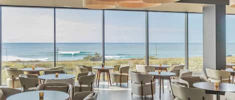 A spacious dining area with large windows offering ocean views, modern pendant lighting, and a clean, minimalist design.