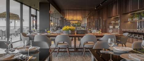 A modern dining area with tables set for two, featuring a central floral arrangement.