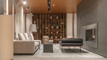 A modern living room with a sofa, armchairs, a coffee table, and a fireplace.