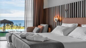 Een moderne hotelkamer met een groot bed, uitzicht op de oceaan en een wandpaneel van hout.