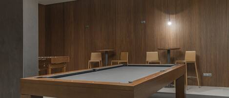 A pool table in a room with wooden paneling and a modern design.