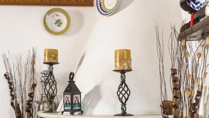 A fireplace with decorative items, a shelf with plates, and a red cushion with "LIVE" text. - Casa La Perla (Rhodes)
