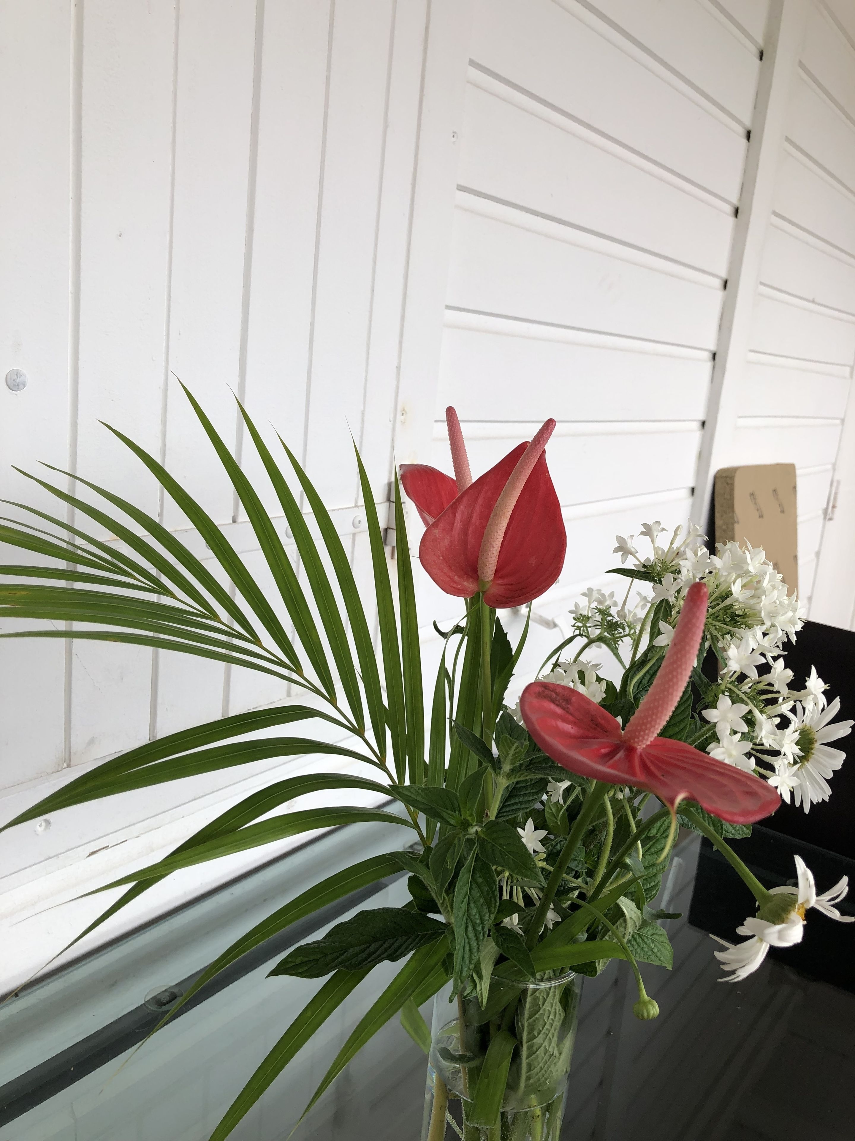 A floral arrangement in a clear vase against a white paneled wall.