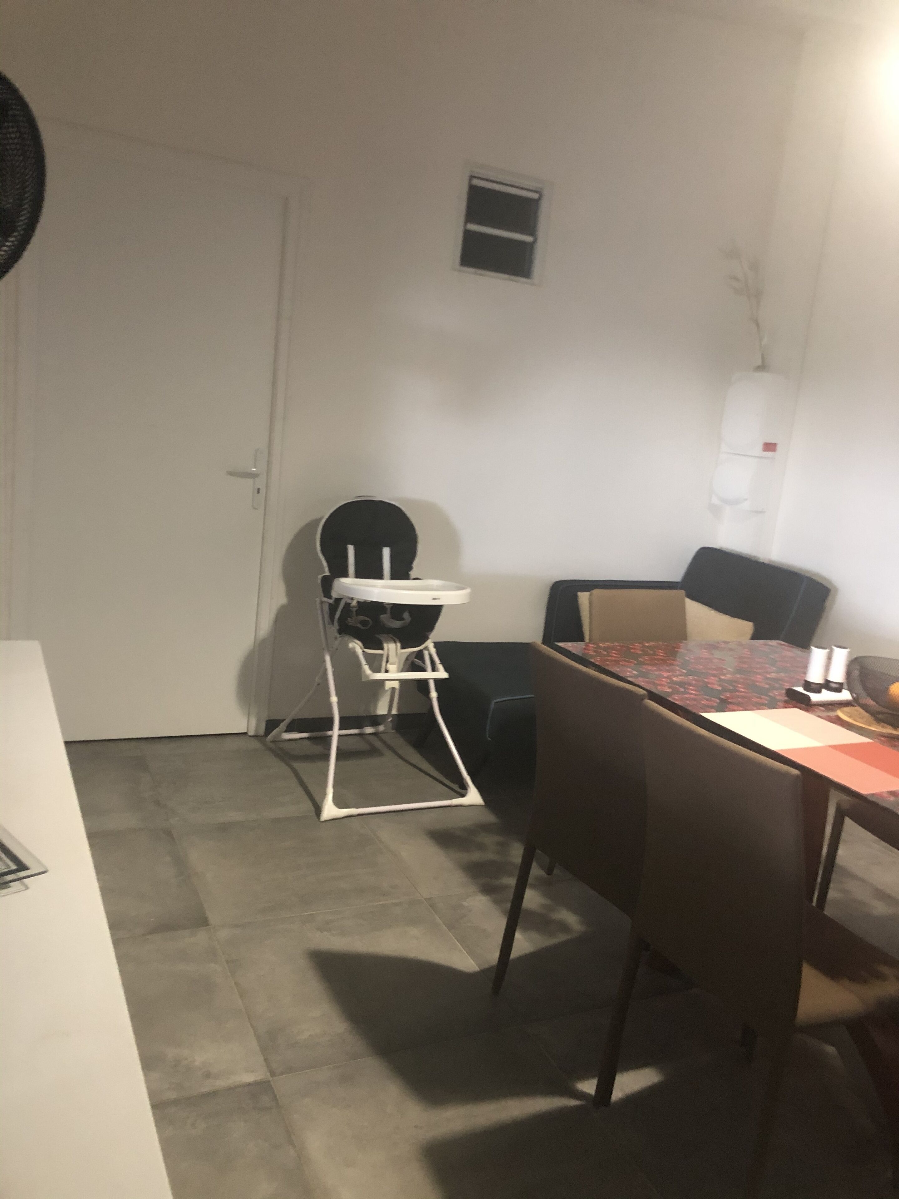 A dining area with a high chair, a table, and chairs.