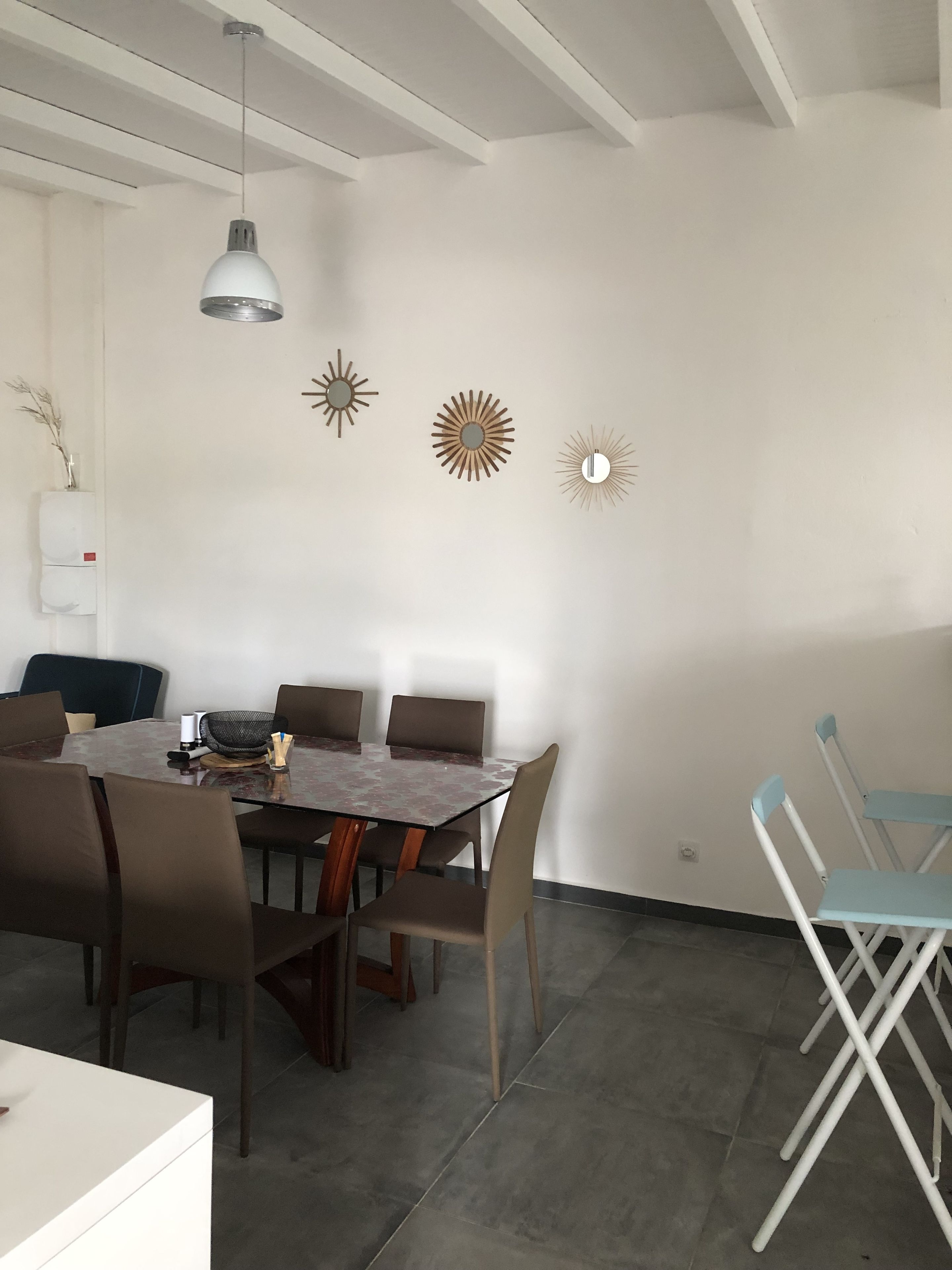 A dining area with a table and chairs, a ceiling light, and wall decorations.