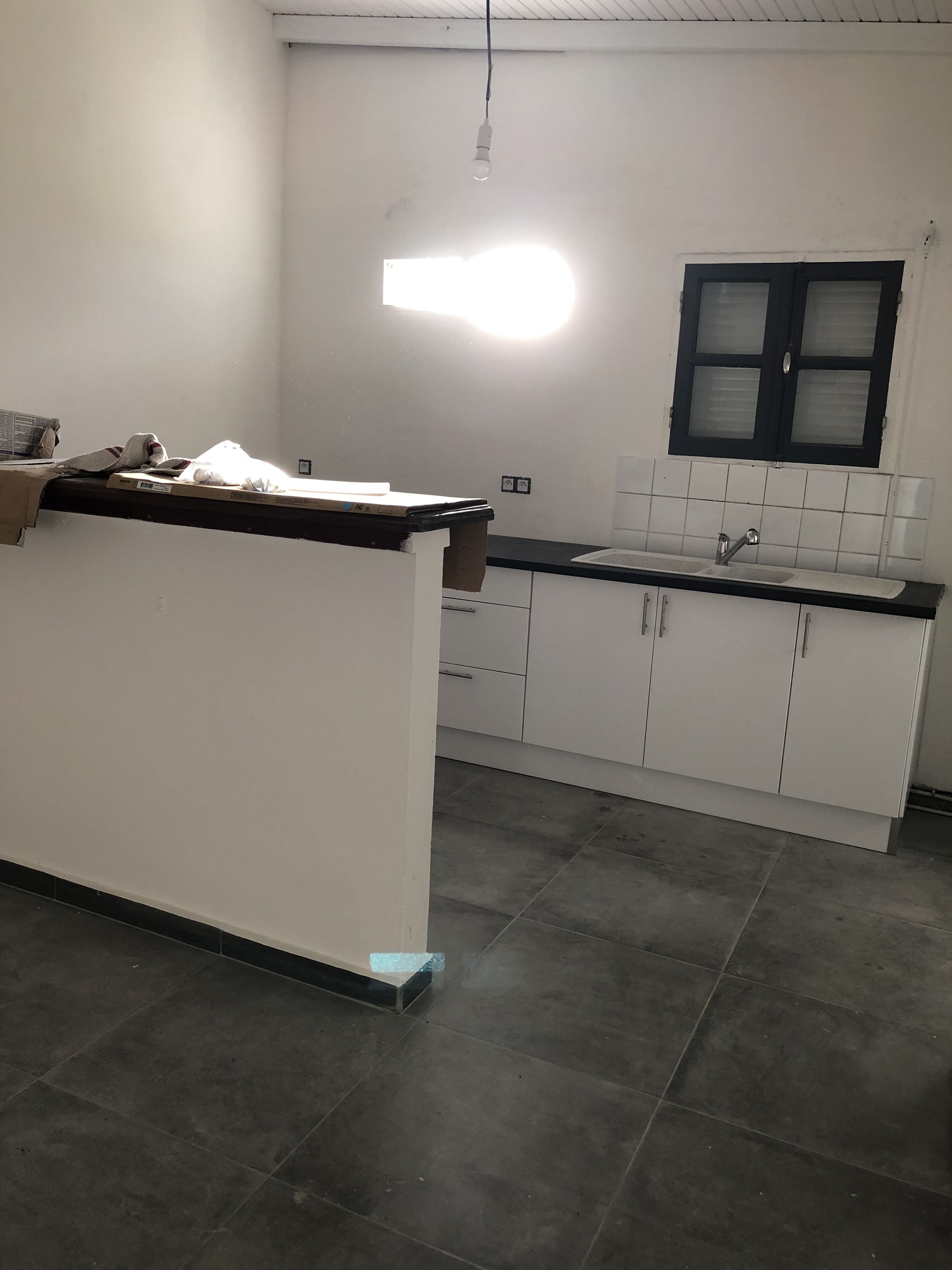 A kitchen with a countertop, cabinets, and a window.