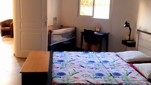 Ein Zimmer mit einem Bett, einem Schreibtisch, einem Stuhl, einer Lampe und einem Fenster.
