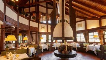Un restaurante con vigas de madera, mesas redondas y un elemento decorativo central.