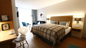 A hotel room with a bed, bedside tables, a desk with a chair, and a window with curtains. - Kamino (Häusern)