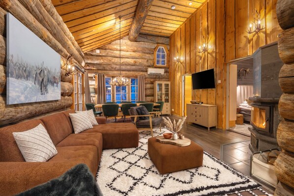 A log cabin interior with a fireplace, a television, and a dining area. - Kuukkeli Hirvas Suite (Saariselka)