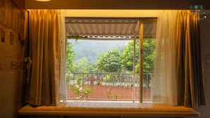 Um quarto com janela dando para um jardim.