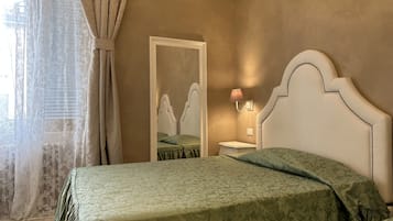 A bedroom with a bed, a nightstand, a mirror, and a lamp.