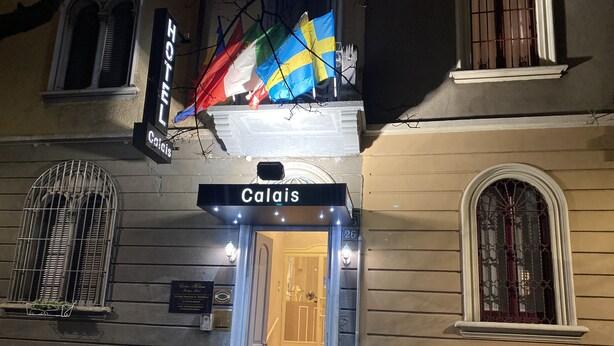 A hotel entrance with a sign reading "Calais" and multiple flags. - Boutique Hotel Calais Milano (Milan)