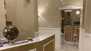A reception area with a marble floor, a globe, and a bar area with stools. - Boutique Hotel Calais Milano (Milan)