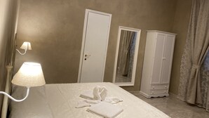 A bedroom with a bed, a wardrobe, a mirror, and a chandelier. - Boutique Hotel Calais Milano (Milan)