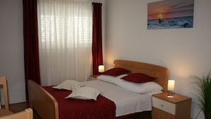 Een slaapkamer met een bed, een nachtkastje van hout en een aan de muur hangend schilderij.