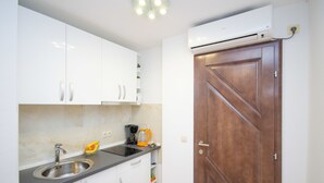 Een keuken met witte kastjes, een roestvrijstalen spoelbak en een houten deur.