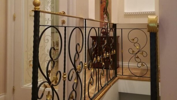 Un escalier orné de rampes en métal noir et d’une main courante en bois.