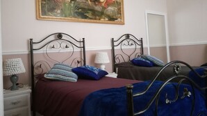 Une chambre avec deux lits, un tableau au mur et une table de chevet avec une lampe.