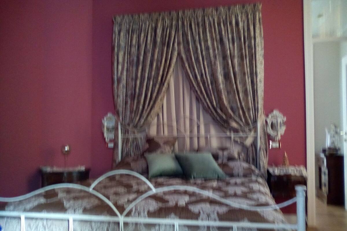 A bedroom with a bed, curtains, a nightstand, and a lamp.