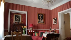 Une pièce comprenant une table à manger, un canapé, un lustre et un tableau au mur.