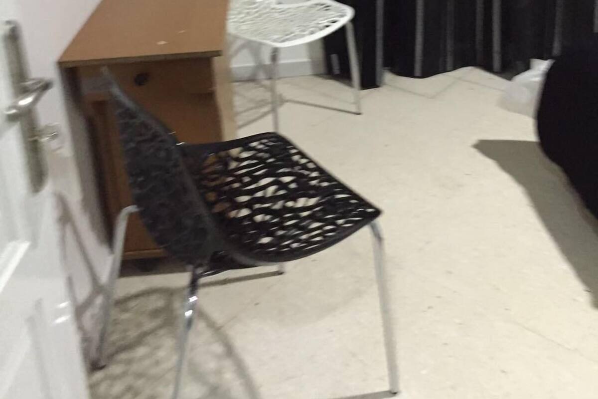 A small room with a desk, a chair, a bed, and a curtain.