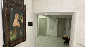A hallway with a framed painting on the left, a door labeled "1ère Etage" on the right, and a small table with a lantern in the distance. - Hôtel Le Calife (Tunis)