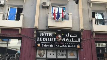 A hotel building with balconies, air conditioning units, and a sign indicating a hotel.