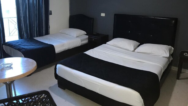 A hotel room with two beds, a small table, and a chair. - Hôtel Le Calife (Tunis)