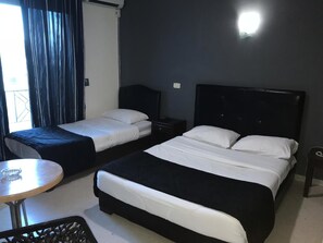 Una habitación de hotel con dos camas, una mesita y una silla.