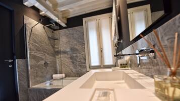 Un bagno moderno con un ampio specchio, un lavandino bianco e un box doccia in vetro.