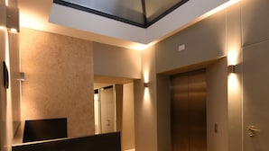 A modern elevator area with a skylight, a reception desk, and a wall-mounted control panel. - Hotel Maison Ducal (Venice)