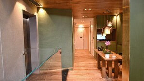 A modern hallway with a glass railing, a wooden table with a vase and a laptop, and a wooden ceiling. - Hotel Maison Ducal (Venice)