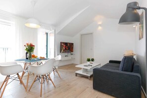 A modern living room with a grey sofa, white chairs, a coffee table, and a TV mounted on the wall. - Apartments and Rooms Stone House (Split)