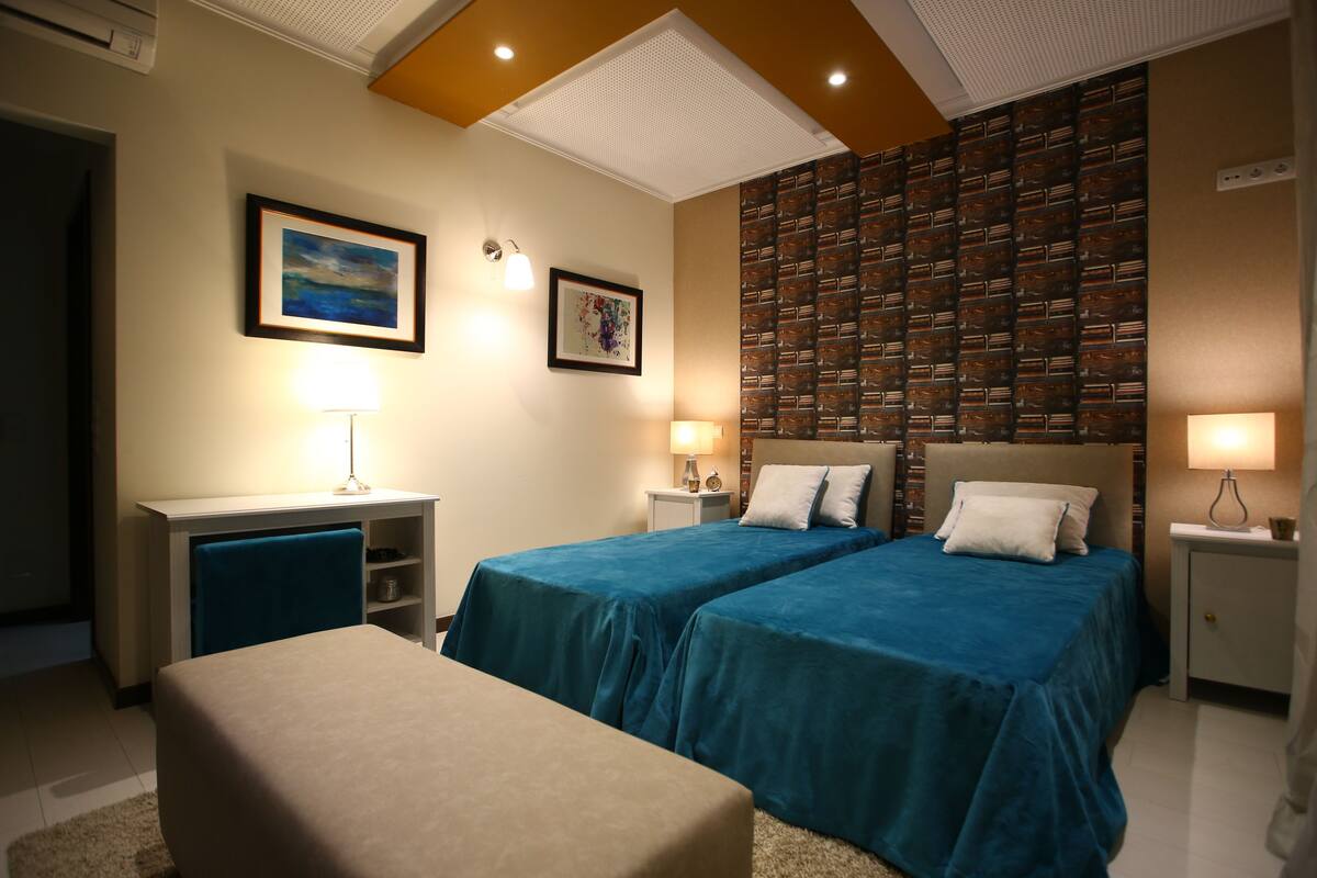 A hotel room with two beds, a desk, a chair, and a large wall unit.
