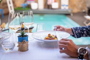A dining table with a plate of food, wine glasses, and a small plant. - Luxury Guest House Opus One (Faro)