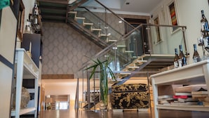 A spacious living area with a modern staircase, a bookshelf, and a coffee machine. - Luxury Guest House Opus One (Faro)