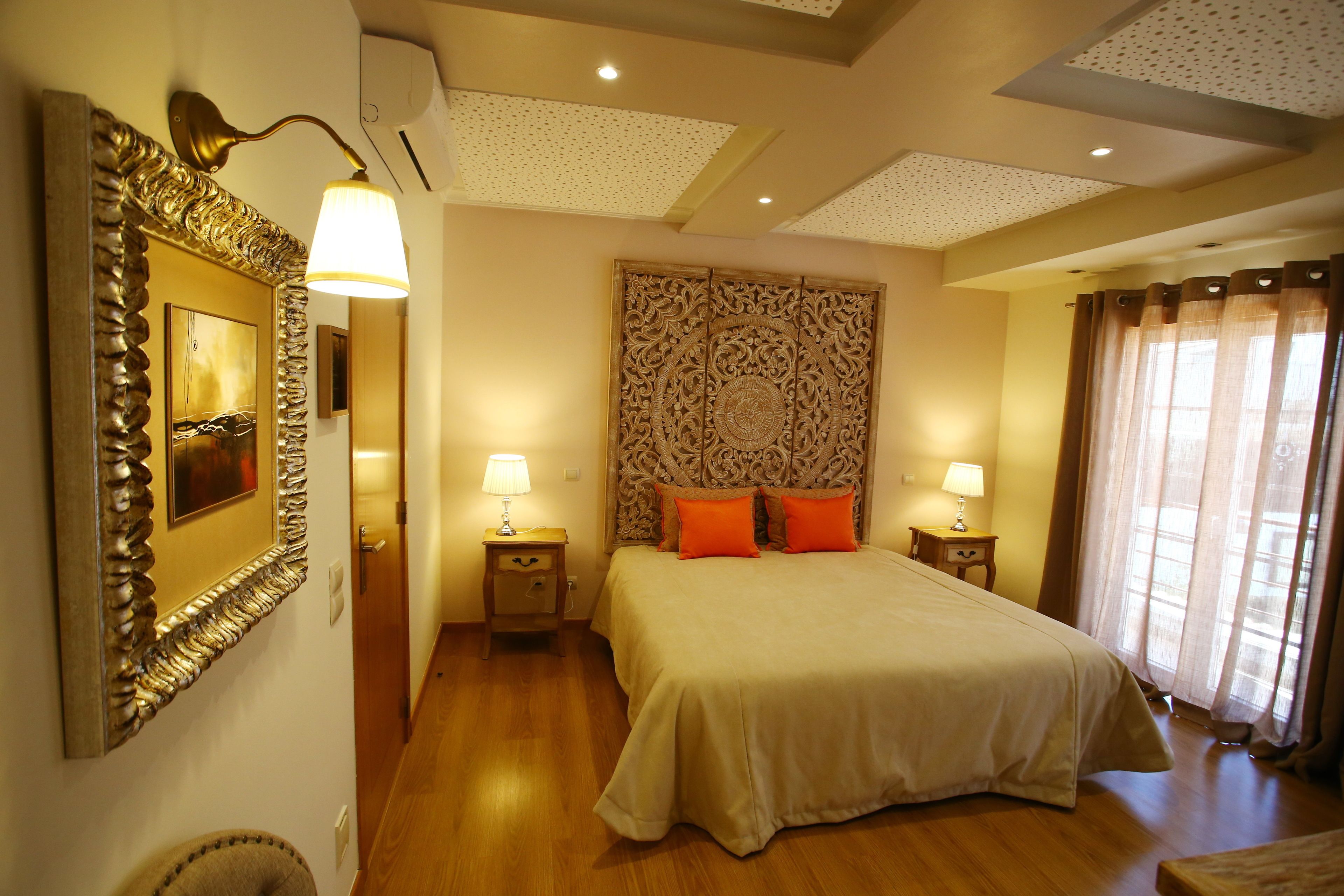 A neatly arranged hotel room with a large bed, two bedside tables with lamps, a decorative headboard, and a framed picture on the wall.