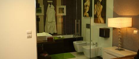 A modern bathroom with a glass shower enclosure, a bathtub, a toilet, and a sink.